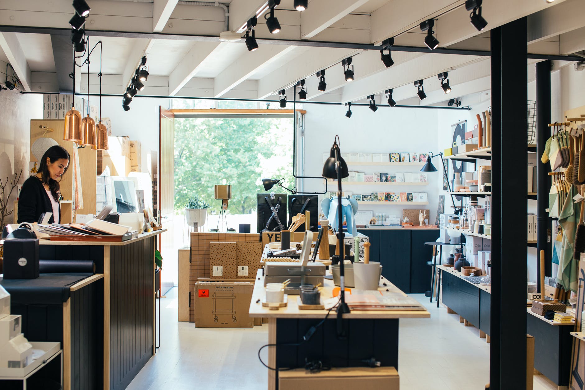 young ethnic female employee standing at counter in creative gift shop