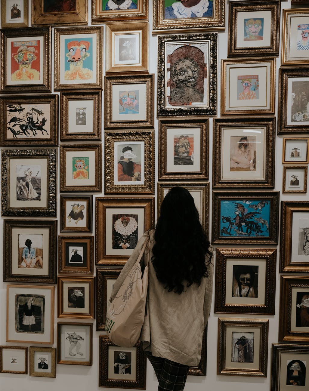 back view of a person looking at art in picture frames