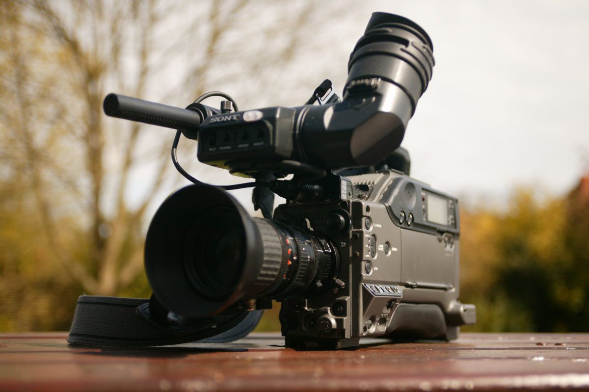 black video camera on brown wooden table